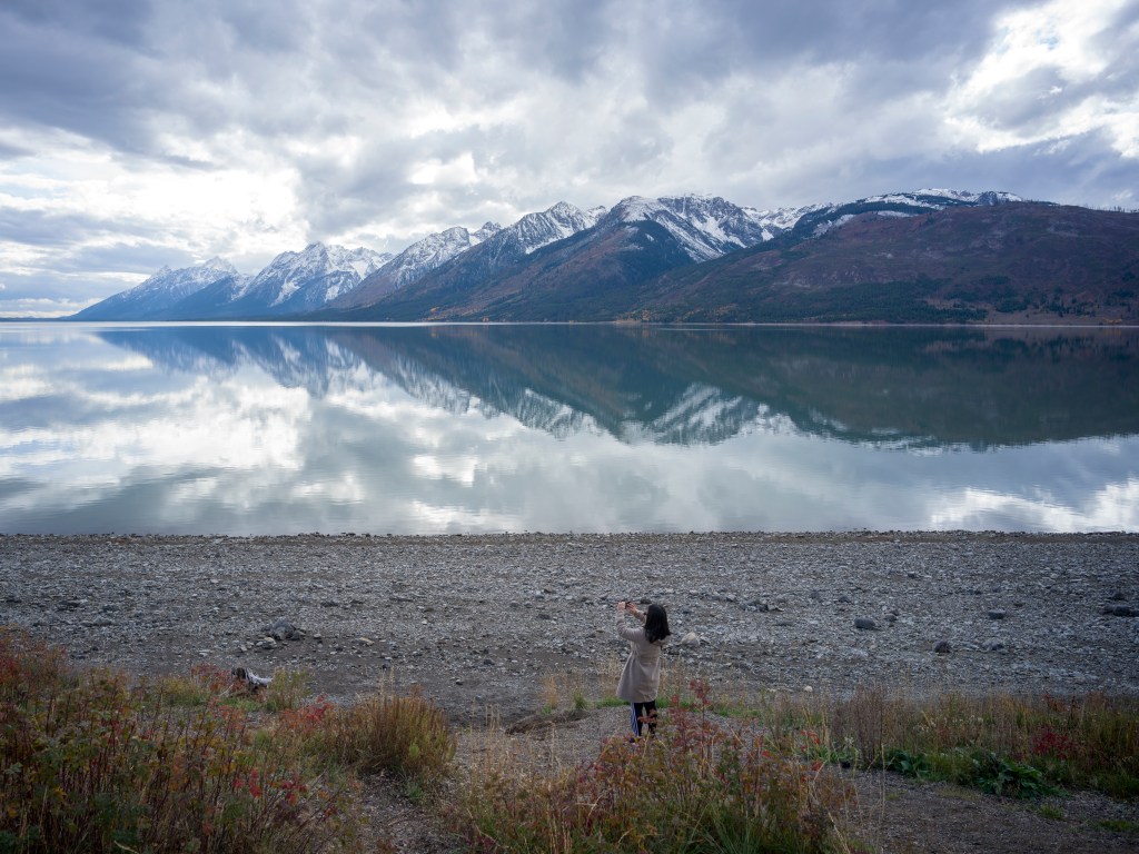 A tourist takes a photo of Jackson Lake in Grand Teton National Park.