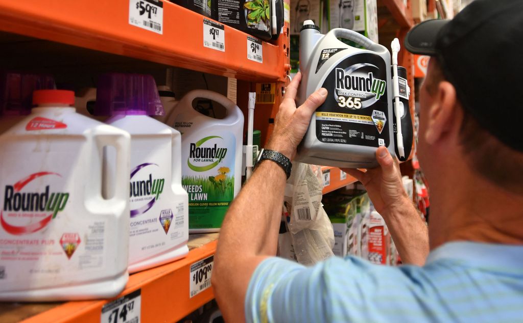 A customer examines a bottle of Roundup 365 weed killer in a store.