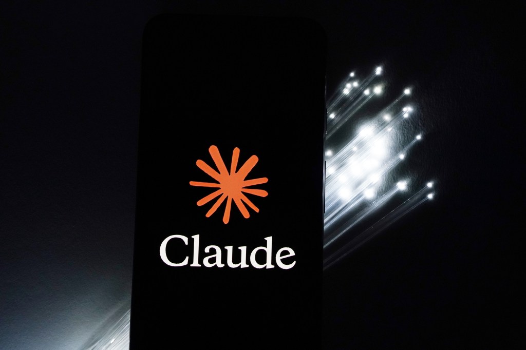 The Claude AI logo displayed on a smartphone next to a printed circuit board.