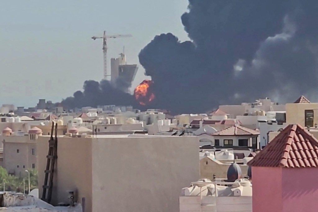 Large orange flames and black smoke billow over residential buildings in Mangaf, Kuwait.