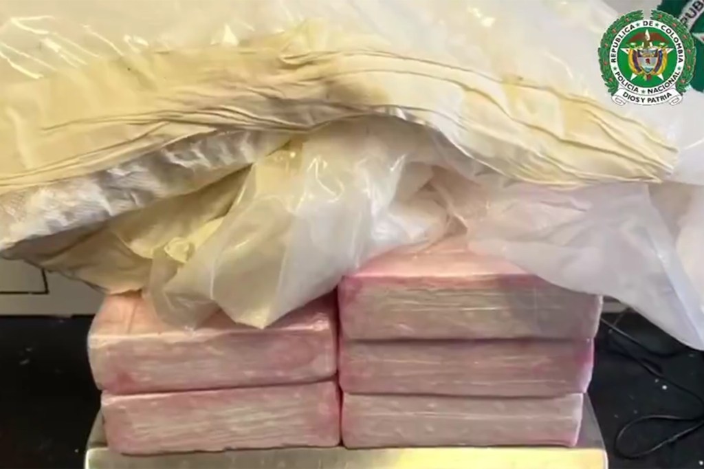 Blocks of cocaine wrapped in pink plastic bags, under a white plastic bag, with the Colombian police emblem in the top right corner.