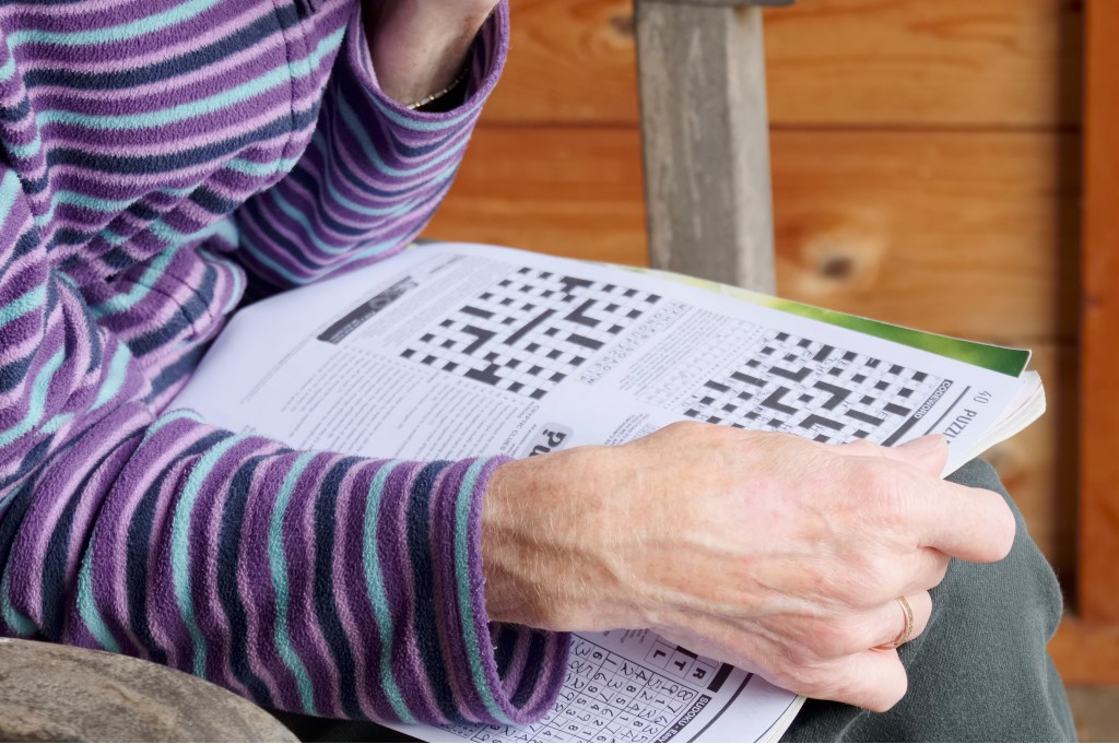 A close-up of a person's hands holding a crossword puzzle book.