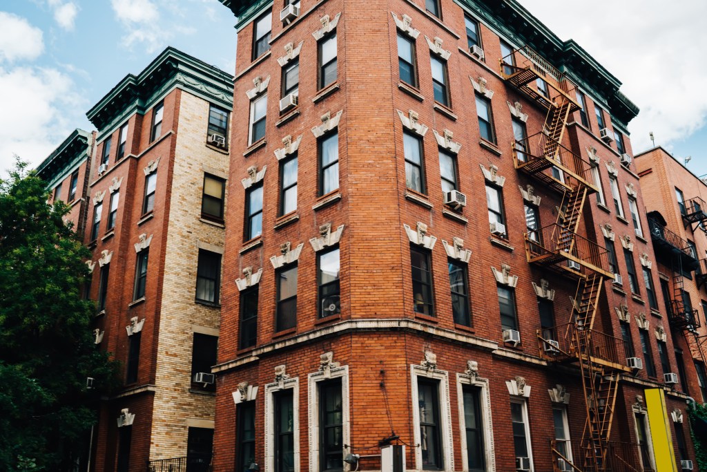 A tall vintage brick building with fire escapes in Brooklyn.