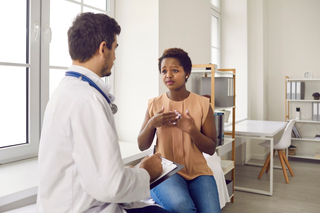 An African-American woman discusses chest pain with her doctor.