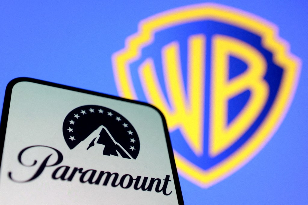 Illustration of the Paramount logo on a phone in the foreground and the Warner Bros. logo blurred in the background.