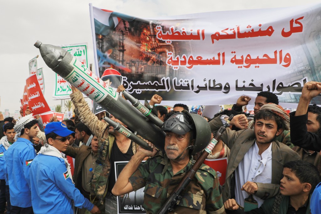 Houthi supporters in Sanaa, Yemen, protest against the Saudi-led coalition, carrying a mock rocket and a banner stating: "All Saudi oil facilities are targets to our missiles and drones."