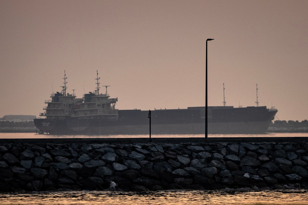 Two ships are anchored off Dubai at sunset.