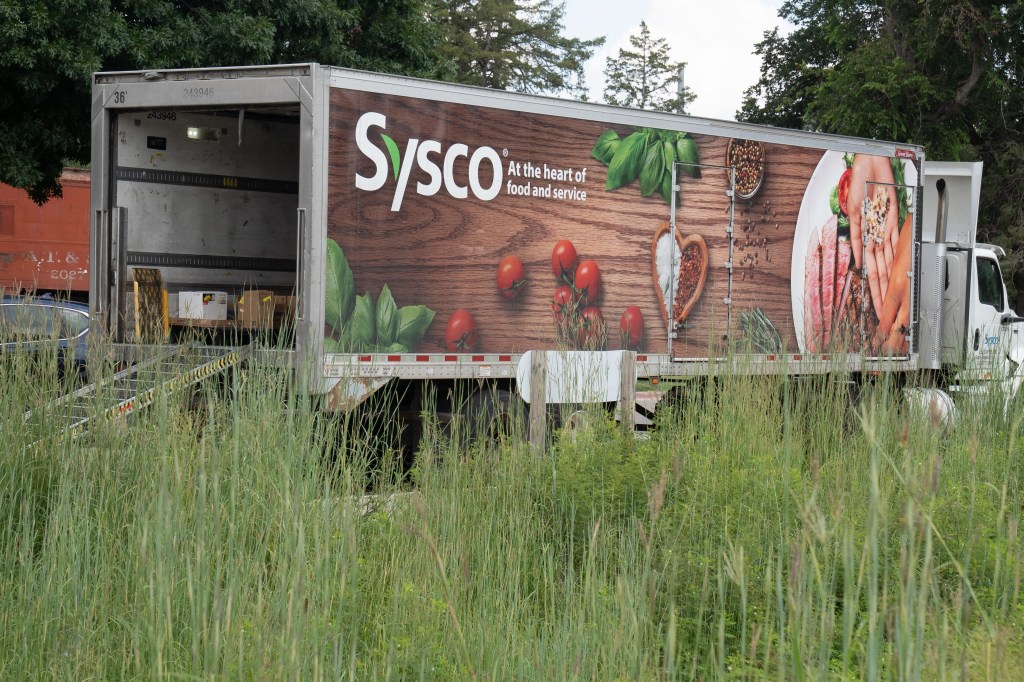 A Sysco food delivery truck with its back open for offloading goods.