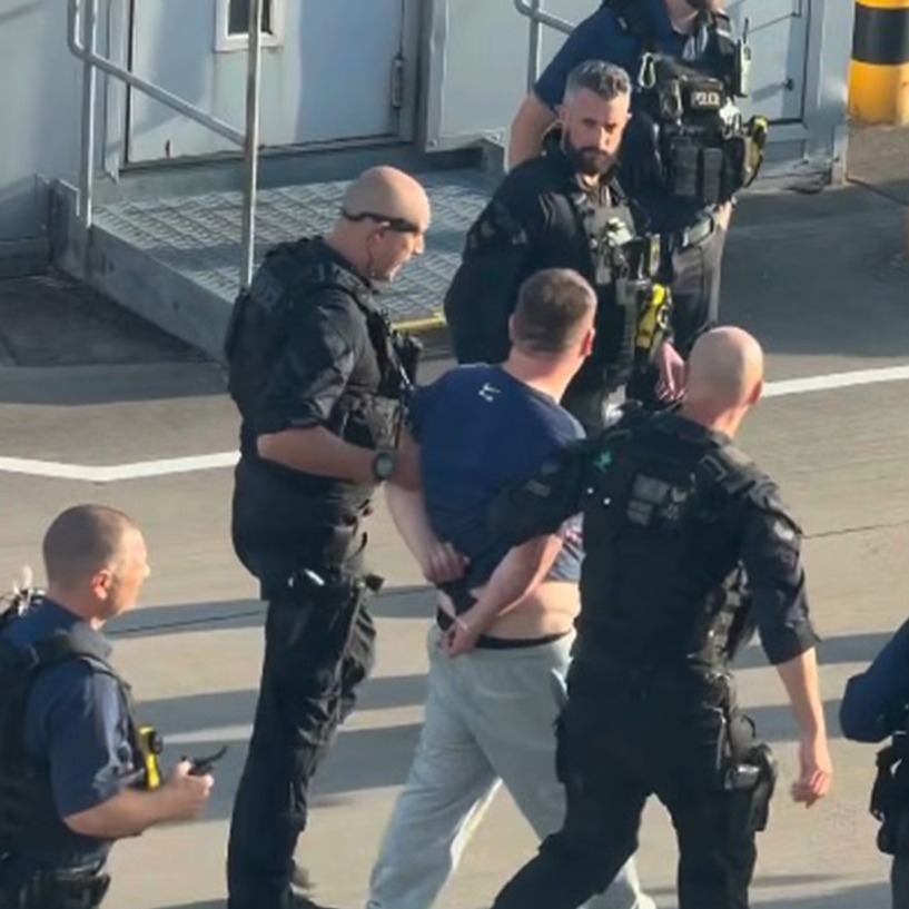 Police escort the man from the plane.