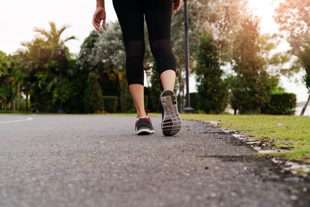 A woman walks on the side of a road.
