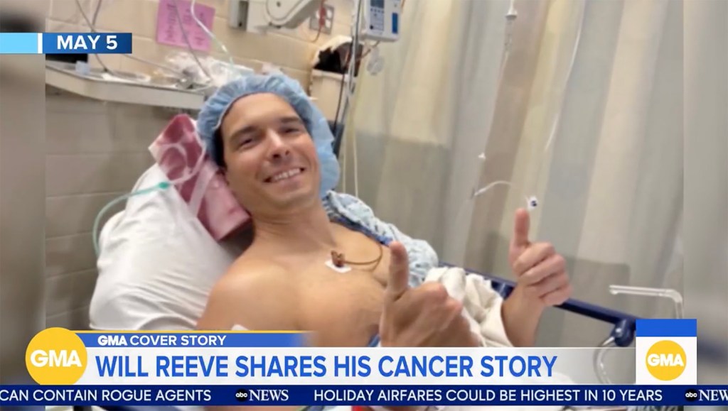 Will Reeve in a hospital bed, wearing a surgical cap and smiling, giving a thumbs-up.