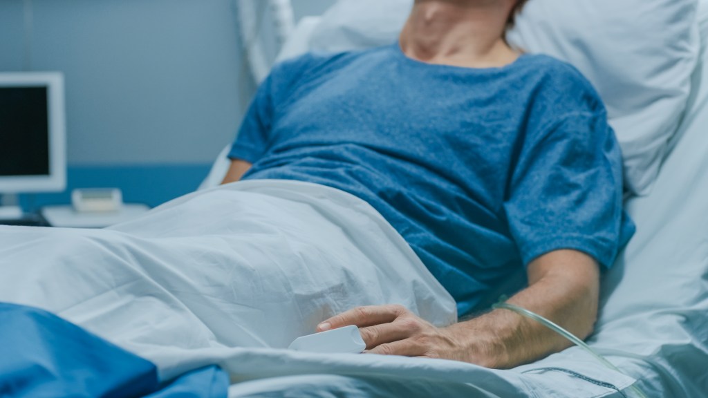 A senior patient sleeping in a hospital bed in a modern geriatrics ward.