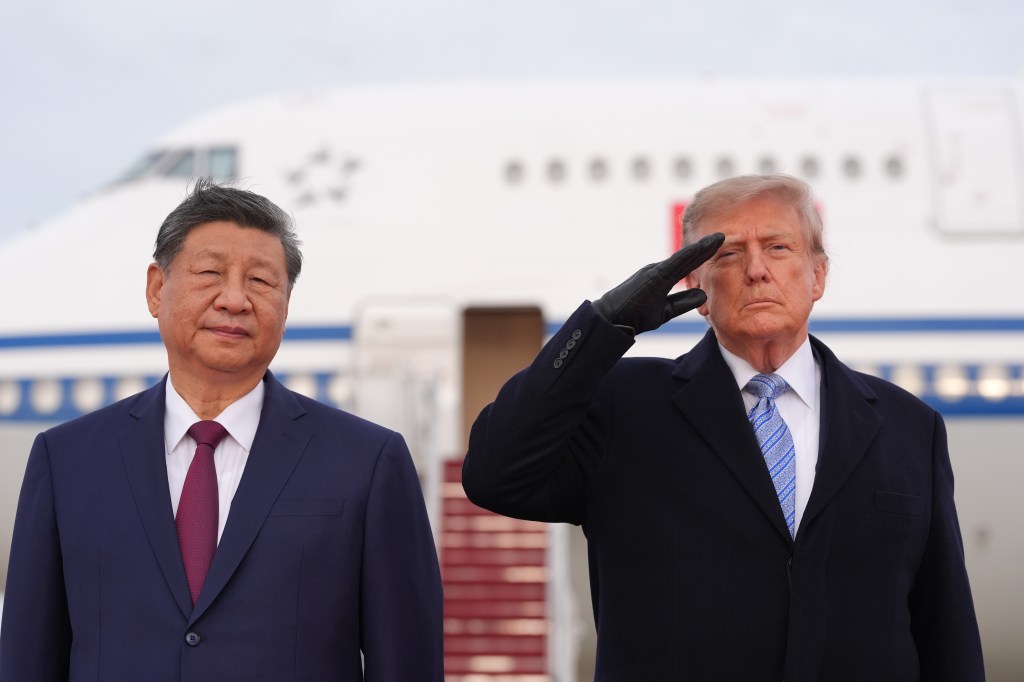 President Donald Trump saluting next to China's President Xi Jinping with an airplane in the background.
