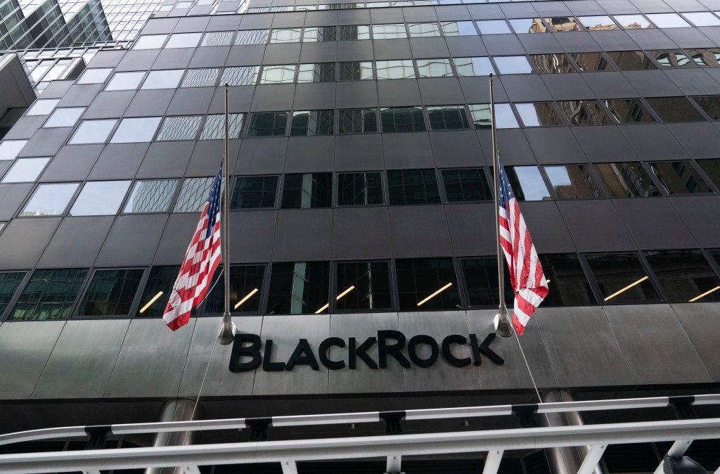 Two American flags fly at half-mast in front of the BlackRock headquarters building.