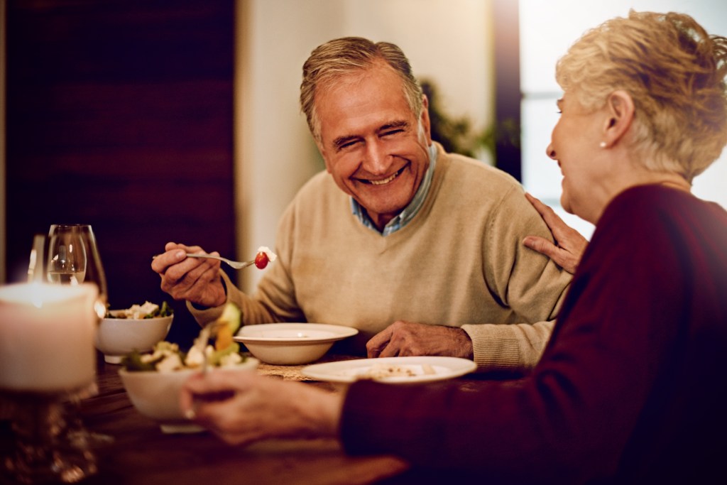 An elderly couple eating dinner together at a fine dining restaurant.