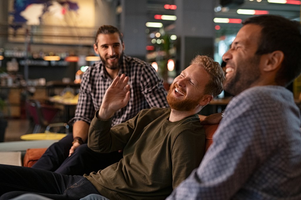 Three friends laughing and enjoying themselves in a pub.