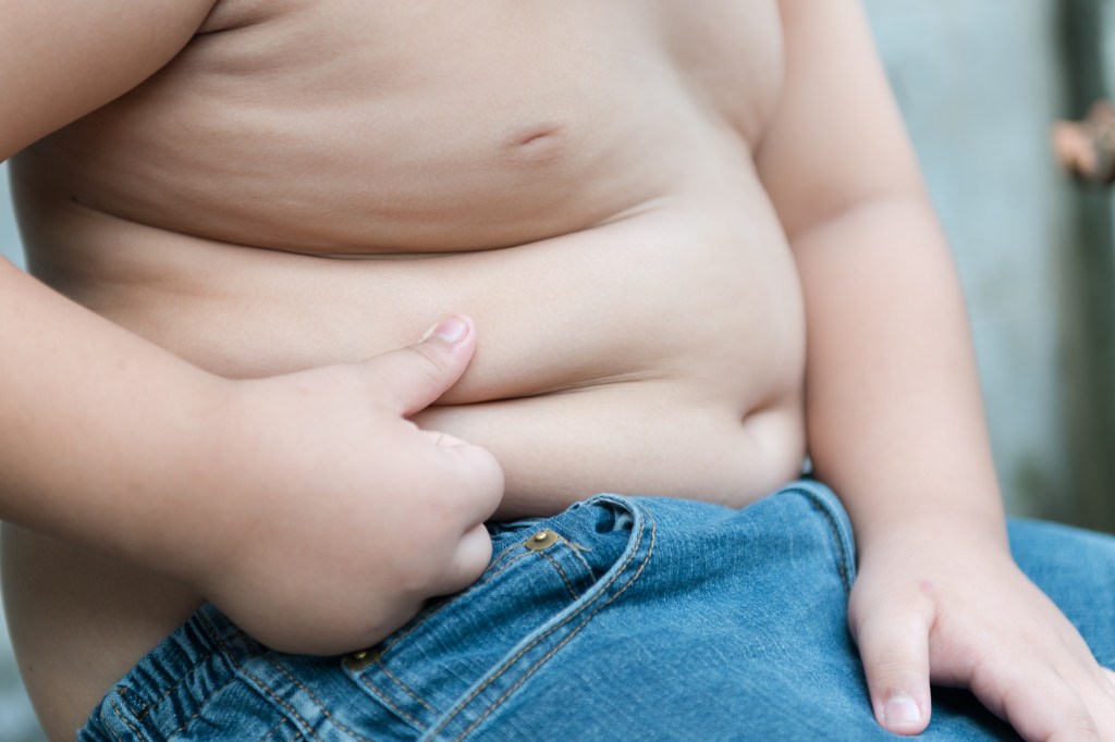 A child's hand pinching the fat on their stomach.