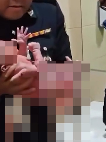A uniformed officer holding a newborn baby boy.