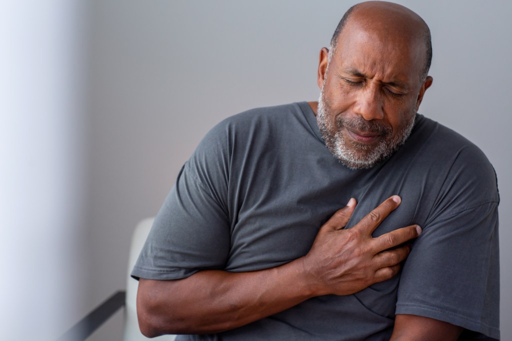 An older man holding his chest in pain.