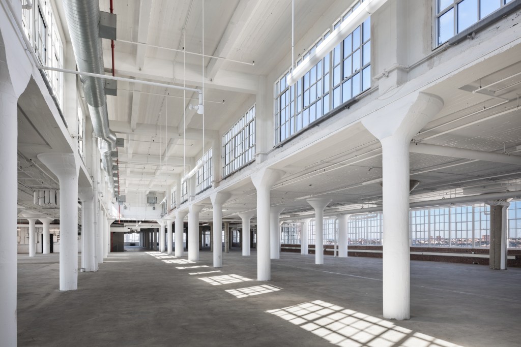 The interior of the Starrett-Lehigh Building, with long rows of columns, large windows, and sunlight casting patterns on the floor.
