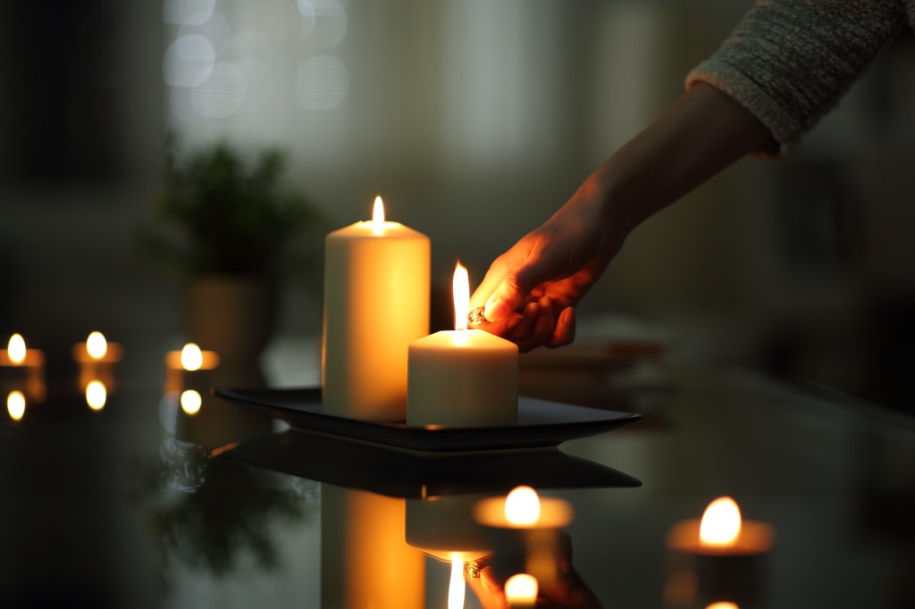 Woman's hand lighting a candle at night.