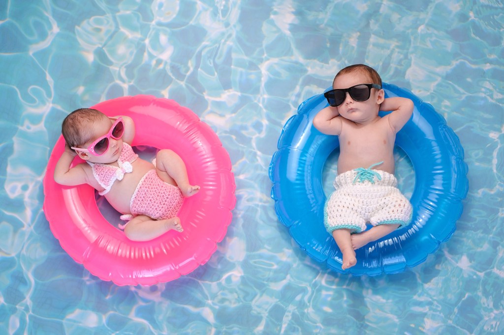 Two babies in sunglasses floating in inner tubes on blue water.