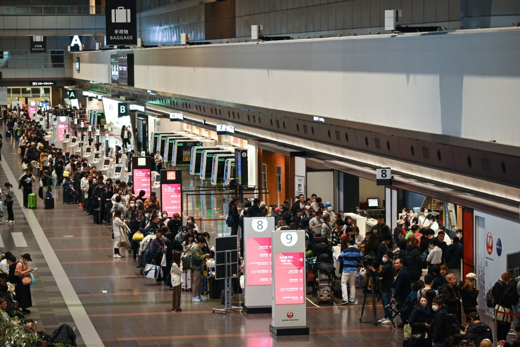 Travelers line up at a Japan Airlines service counter