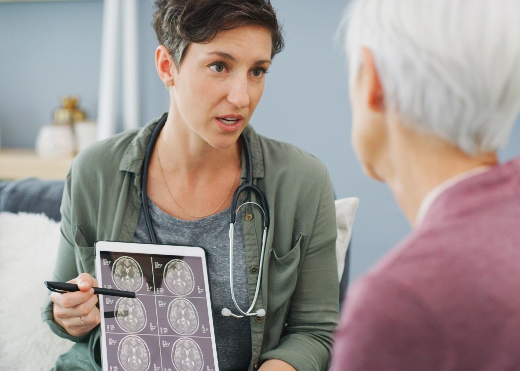A female doctor showing brain scan results on a tablet to an older patient.
