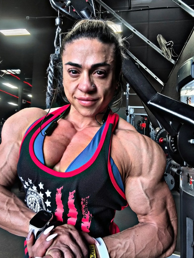 Female bodybuilder Marianne von Gierke flexing her muscles in a gym.