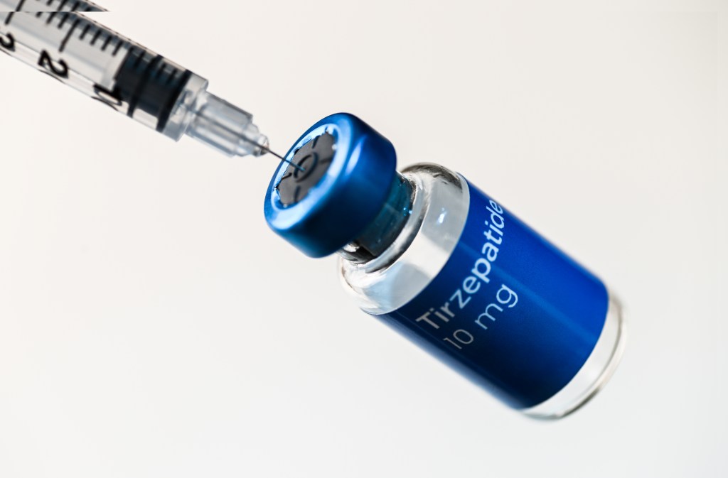 A syringe needle inserted into a vial of Tirzepatide.