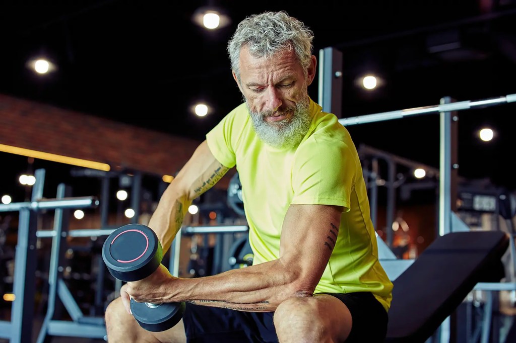 a older man lifting a weight at a gym