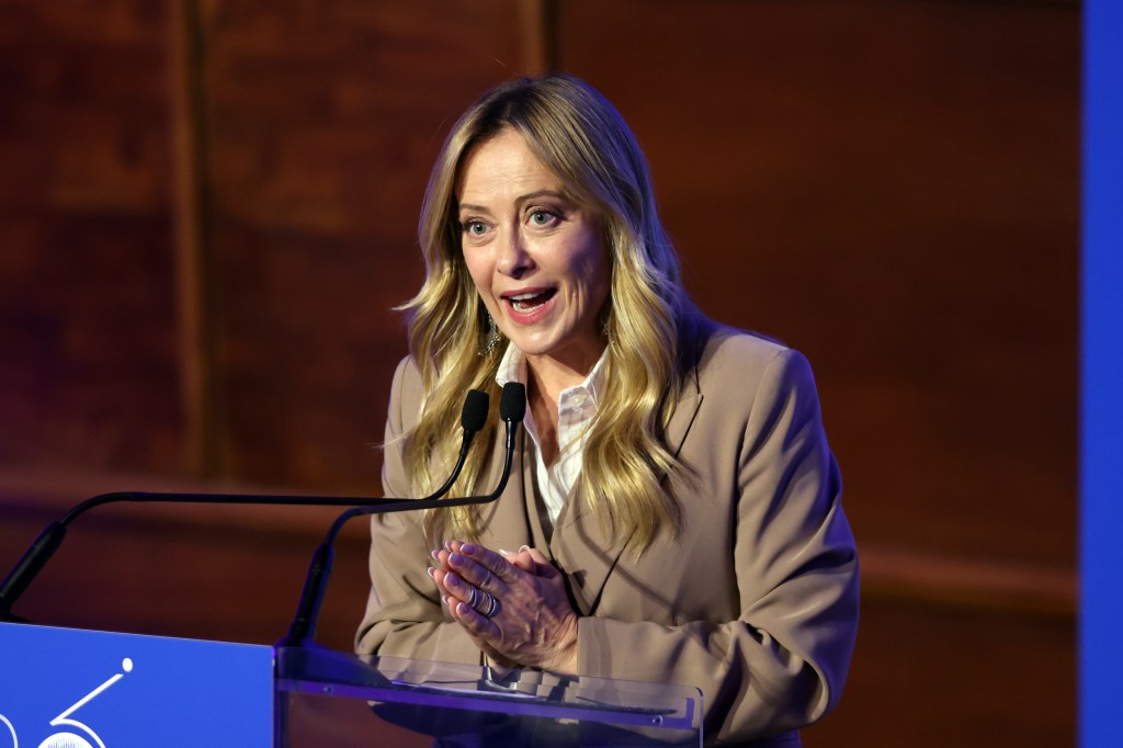Italian Prime Minister Giorgia Meloni giving a speech at a podium.