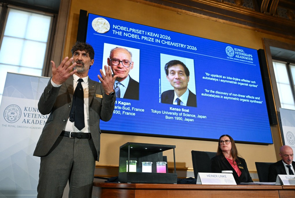 Heiner Linke, left, chair of the Nobel Committee for Chemistry, explains the field of research of Nobel Prize winners Henri Kagan of France and Kenso Soai of Japan, displayed on the screen in the background, during a press conference to announce the winners of the 2026 Nobel Prize in Chemistry at the Royal Swedish Academy of Sciences in Stockholm, Sweden on Wednesday.