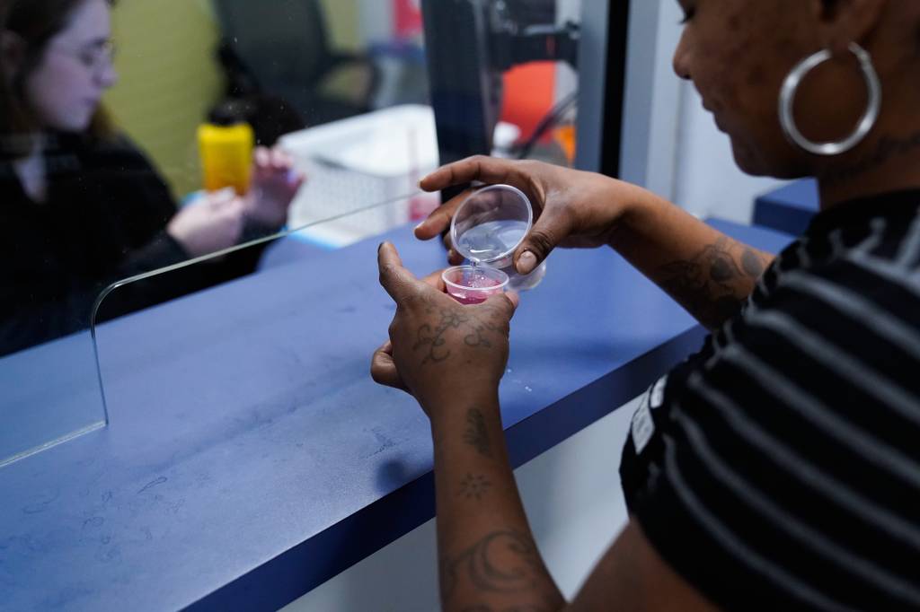 Alicia Bermudez adds water to her methadone in small plastic cups