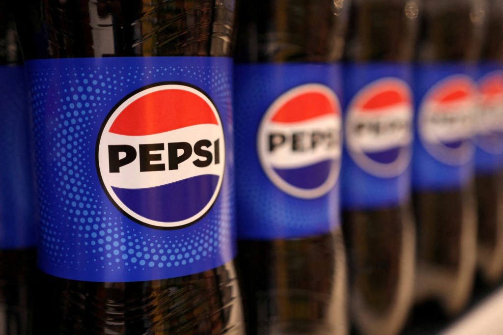 Bottles of Pepsi are displayed on a shelf in a supermarket.