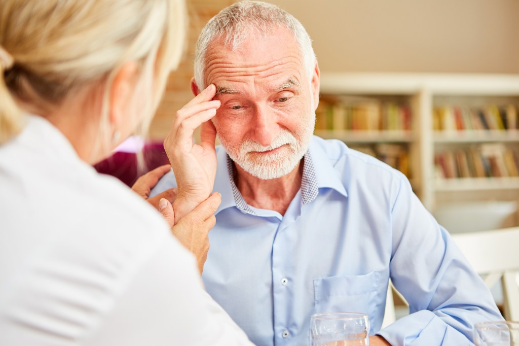 A female doctor comforts a senior patient.