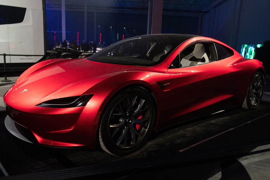 A red Tesla Roadster on display in an indoor showroom.