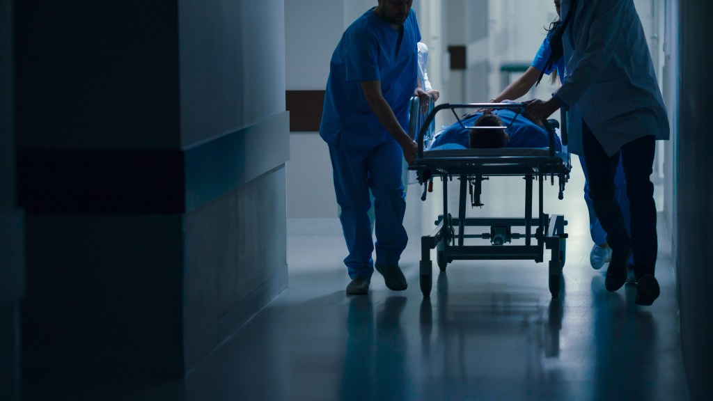 Doctors, nurses, and paramedics push a gurney with a seriously injured patient down a hospital hallway toward the operating room.