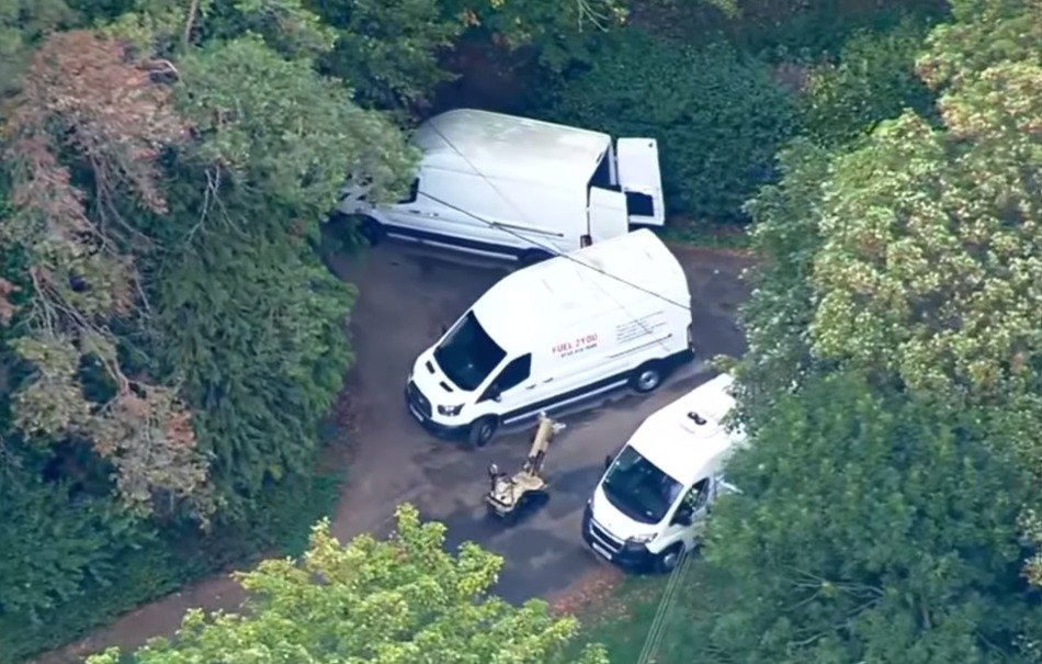 An aerial view of a bomb squad robot near suspected vans.
