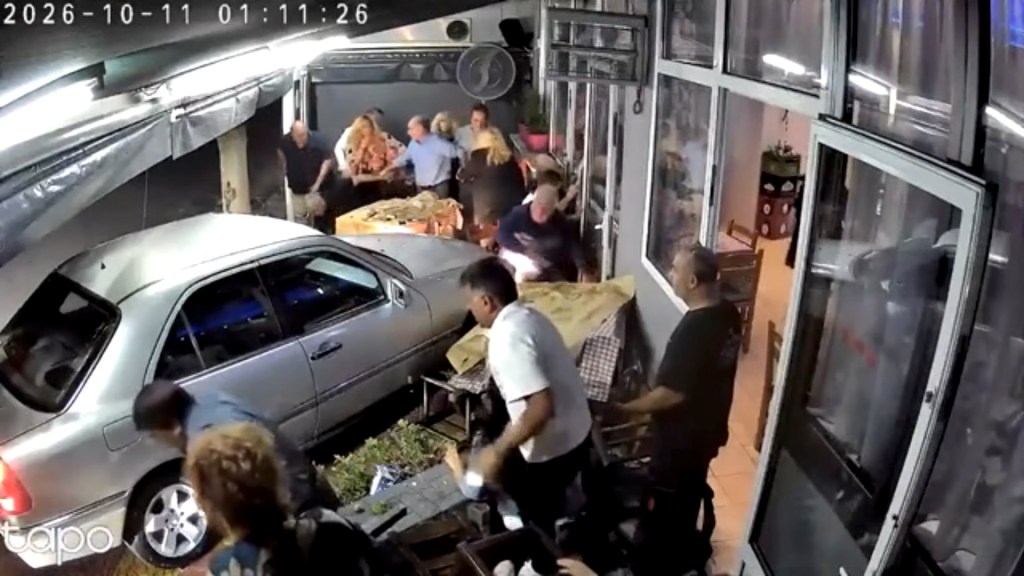 CCTV footage of a silver car that crashed into the outdoor seating area of a tavern, sending patrons scattering.